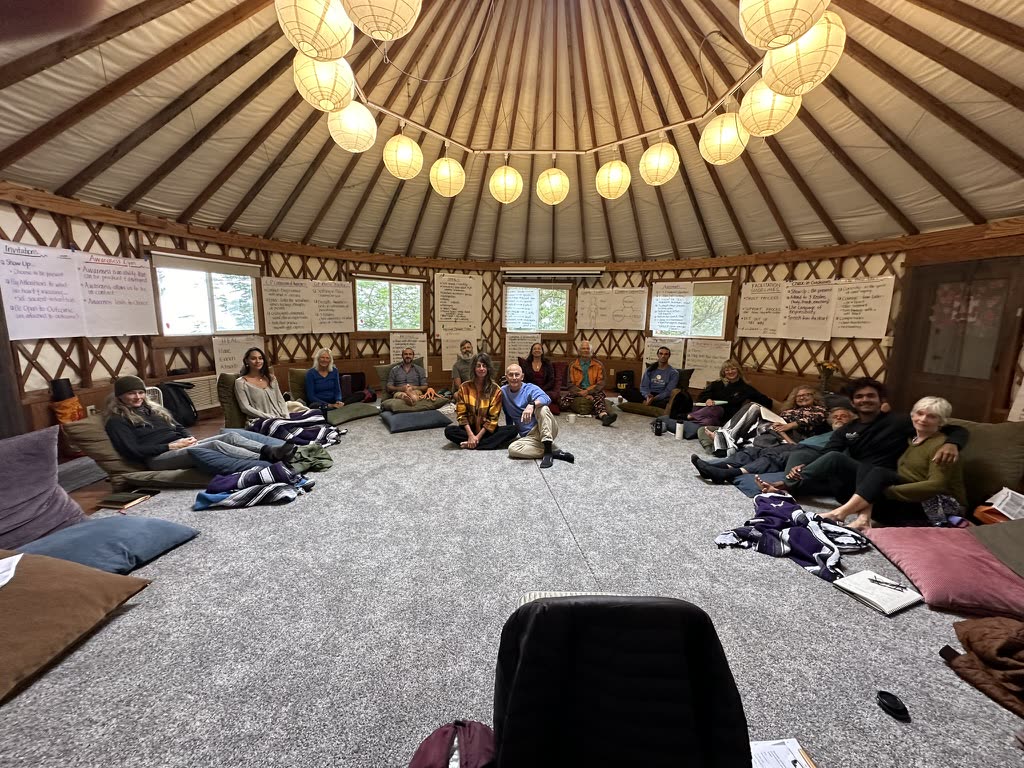 A facilitated circle seated on cushions in a yurt at Esalen