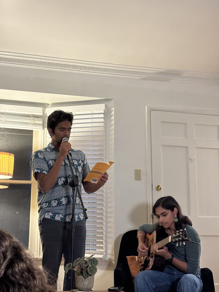 Singing into a mic while holding a lyric sheet at a living-room open mic
