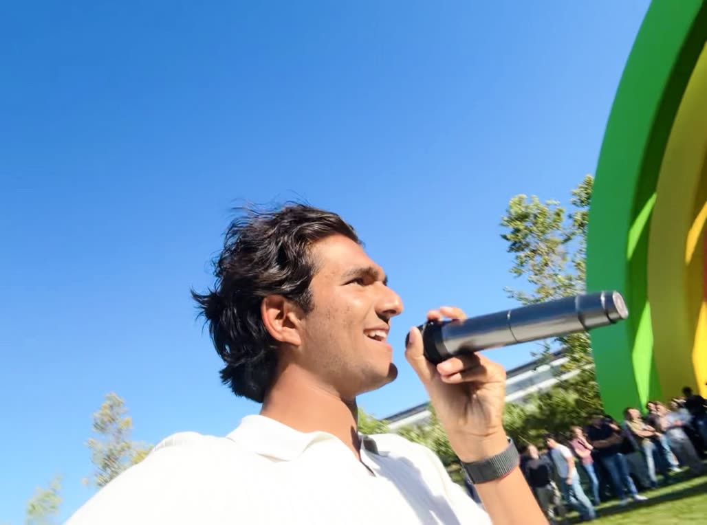 Holding a mic outdoors with a crowd gathered at Apple Park