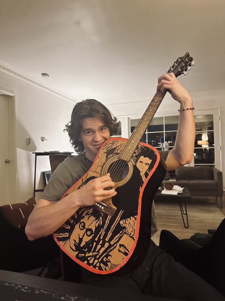 Holding the painted guitar up to the camera